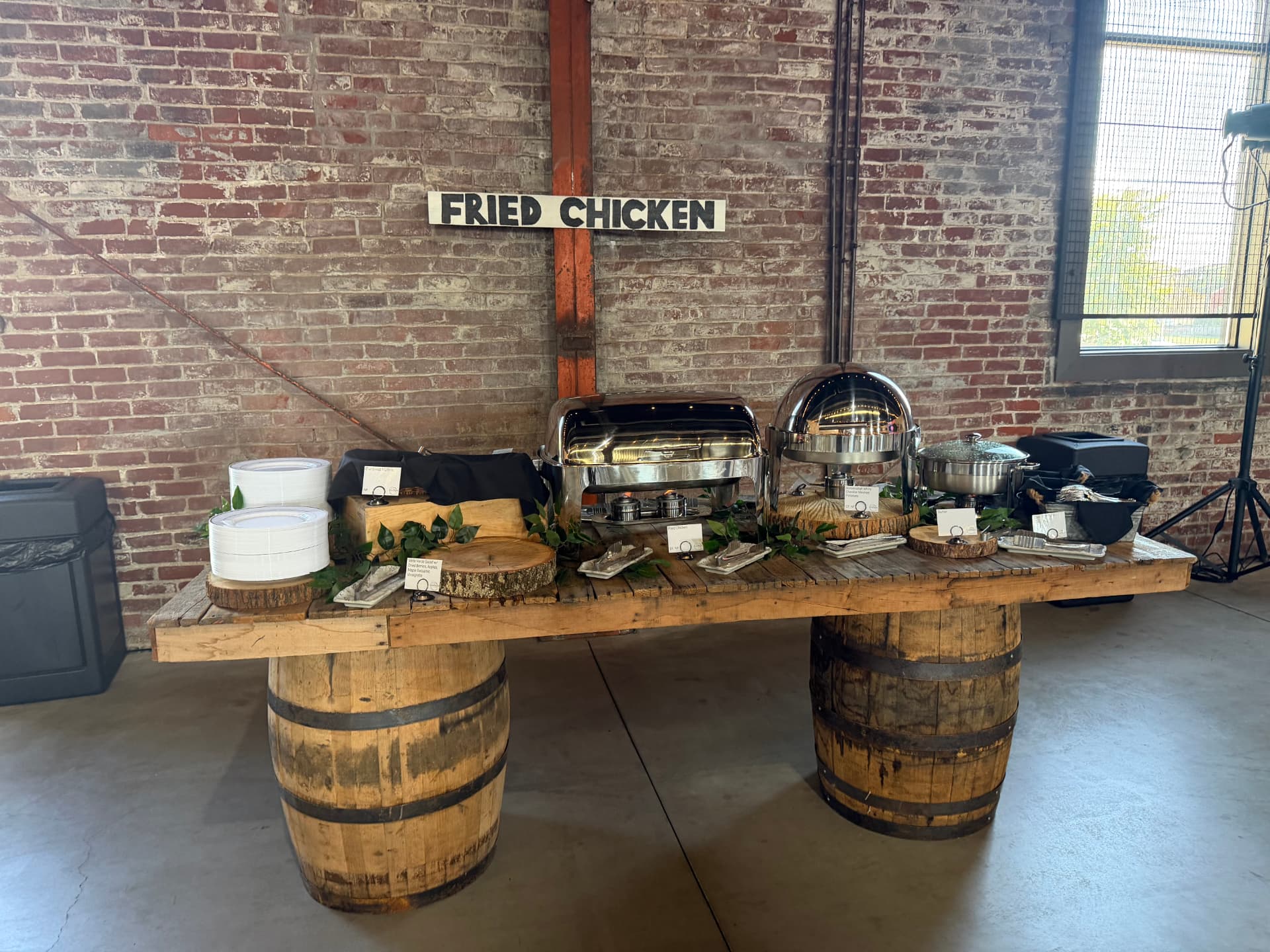 Catering buffet station on barrel tables against exposed brick