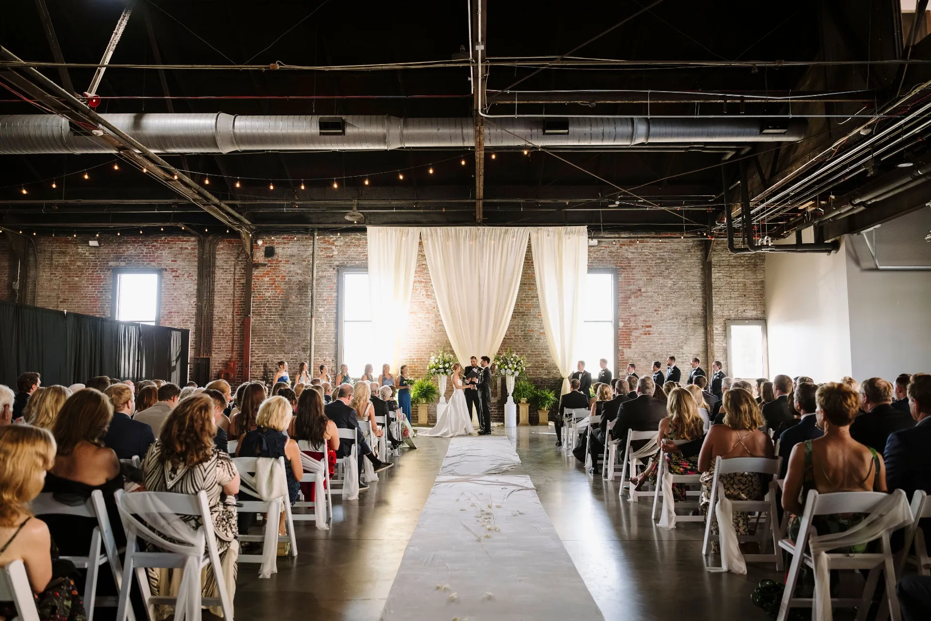 Wide ceremony shot down the aisle toward the draped altar