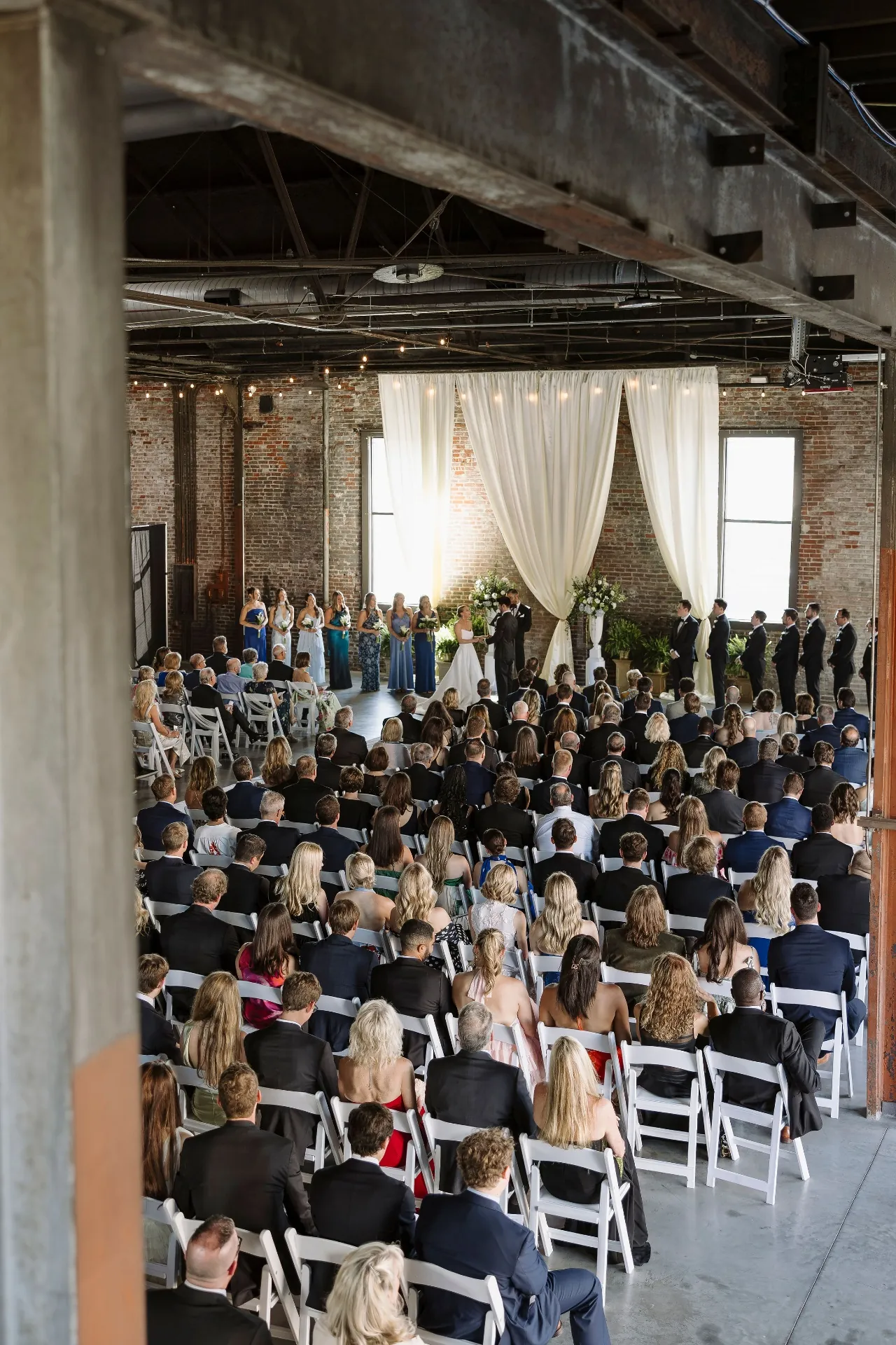 Bride and groom exchanging vows in front of ivory drapery
