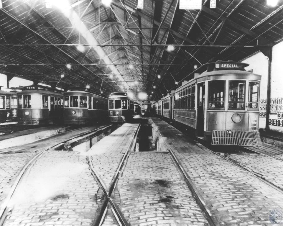 Historic interior photo of streetcars on tracks inside the car barn