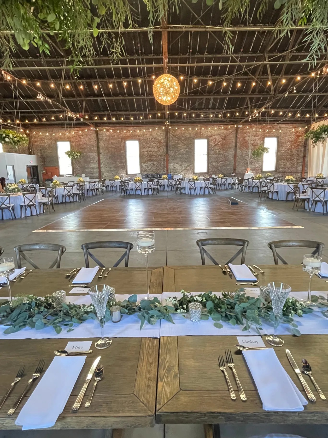 Wedding reception with hanging greenery and farmhouse tables