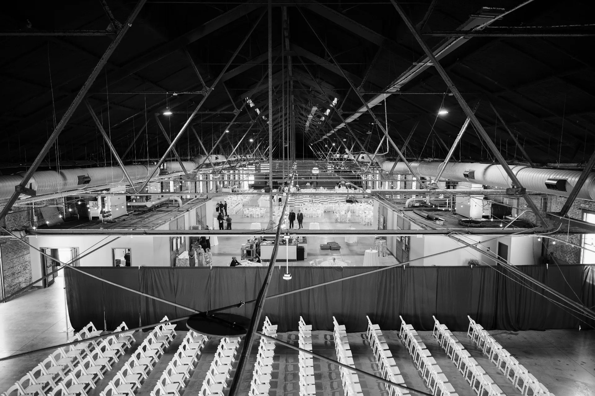 Black and white view from the rafters looking down the length of the hall